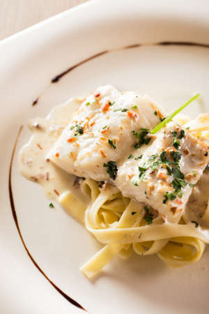 Cooked hake with sauce and pasta.の写真素材
