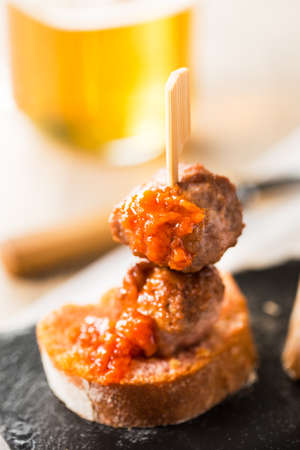 Meatball tapa with tomato on slice of bread.の写真素材