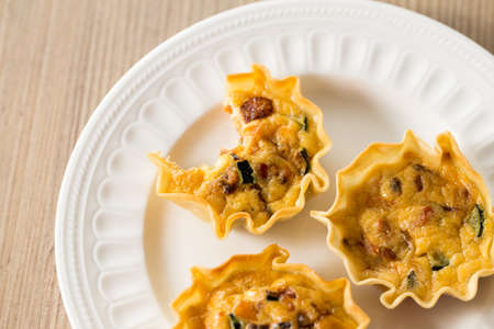 Delicious mini quiche with vegetables and pumpkin on a wooden table.の写真素材