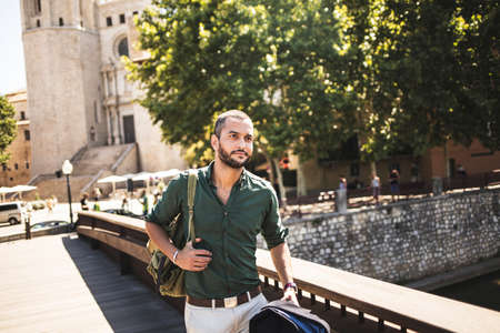 Handsome bearded man walking on bridge and looking away. Summertimeの写真素材