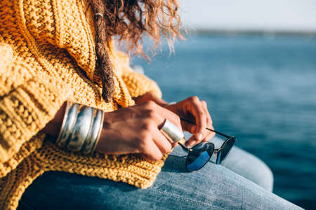 Side view of young woman hands sitting and holding a sunglass.の写真素材