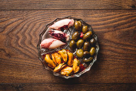 Traditional spanish appetizer with mussels, olives and squid. Top view wooden table.の写真素材