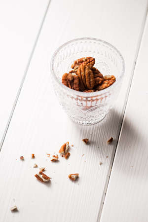 Pecan nuts in a glass on white wooden table.