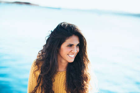 Portrait of young woman looking away while sitting on pier.Summertime