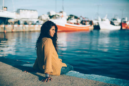 Young woman sitting on pier and looking away. Sunnyの写真素材