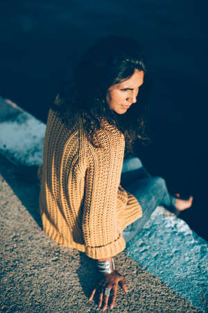 Young woman sitting on pier and looking away. Vintage editionの写真素材