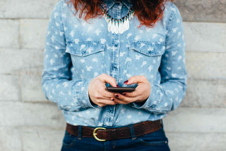 Woman hands using phone against urban concrete wallの写真素材