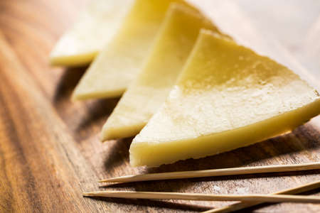 Spanish cheese sliced on wooden board with toothpicks.の写真素材
