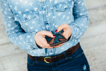 Woman hands using phone against urban concrete wallの写真素材
