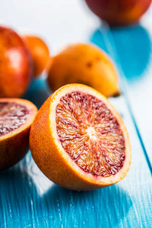 Halves of bright juicy red oranges on blue wooden backgroundの写真素材