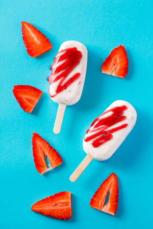 Close-up of two ice cream pops with strawberry and berry jam on blue backgroundの写真素材