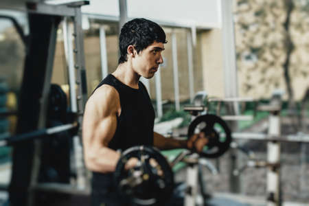 Muscular man doing exercise with dumbbells in gymの写真素材