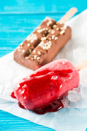 Strawberry ice cream pop with topping against of chocolate unfocused ice cream pop