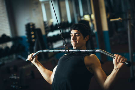 Muscular man doing exercise with dumbbells in gym