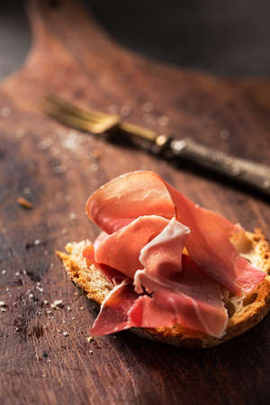 Close-up of delicious ham slices with white bread on wooden board