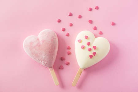 Two heart-shaped ice cream covered with confetti on pink backgroundの写真素材