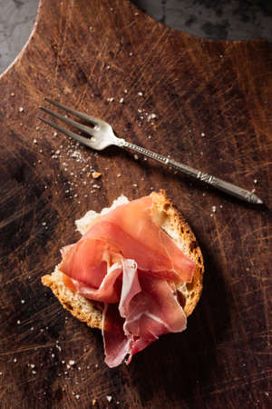 Delicious ham slices with white bread on wooden board, rustic vintage.の写真素材