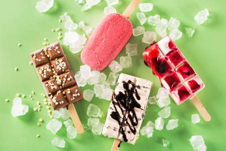 Close-up of various delicious ice creams with ice on green background