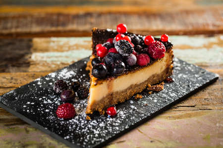 Slice of delicious cheesecake with berry fruit on a wooden table.の写真素材