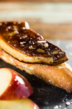 Snack of fried foie gras and red apple on a slice of bread.の写真素材