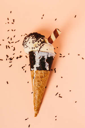 Vanilla ice cream cone melting with waffle tube isolated on pink background.