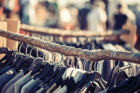 Close-up of clothes hanging on rail at street market in sunlight.Bokehの写真素材