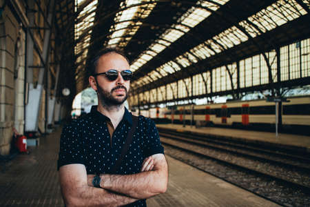 Portrait of bearded traveler waiting for train on railway platform