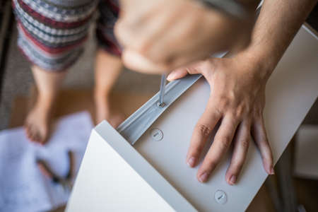 Close up of unrecognizable person in colorful leggings tightens screw with a screwdriver lying on the floorの写真素材