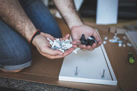 Close up of hands holding handful of fitting and screws for the assembling furnitureの写真素材