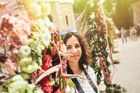 Portrait of young  brunette enjoying vacation and posing nearby flowers on blurred town background.の写真素材