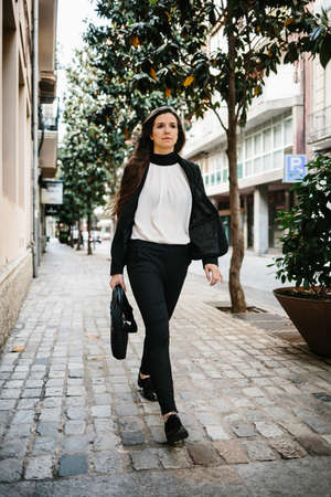 Confident woman walking in the street and looking away. Vertical outdoors shot.の写真素材