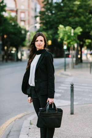 Serious businesswoman standing on a crossroad and looking at camera. Vertical outdoors shot.の写真素材