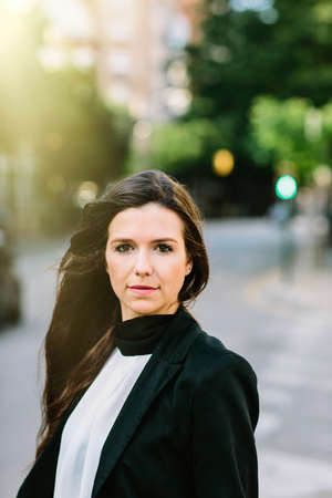 Attractive businesswoman looking at camera standing in the street. Vertical outdoors shot.の写真素材