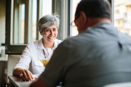 Laughing old lady sitting at table in restaurant.の写真素材