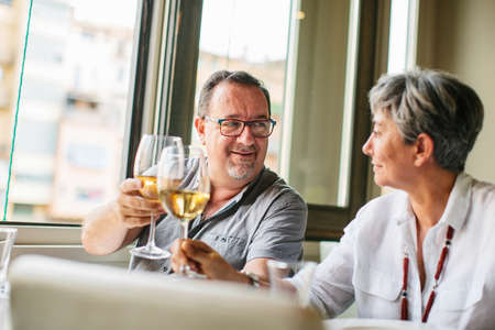 Laughing mature couple sitting at table in restaurantの写真素材