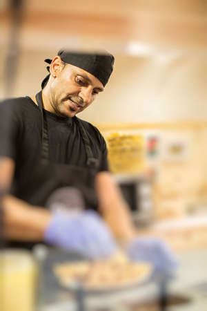 Man in uniform and gloves cooking in food truck.