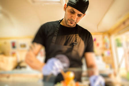 Man in uniform and gloves cooking in food truck.の写真素材