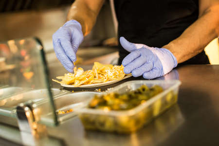 Crop faceless shot of person in gloves cooking nachos in food truck.の写真素材