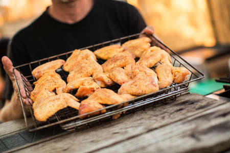 Crop man holding basket with roasted chicken wings.の写真素材