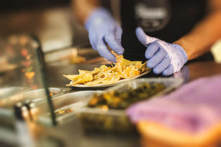 Crop faceless shot of person in gloves cooking nachos in food truck.の写真素材