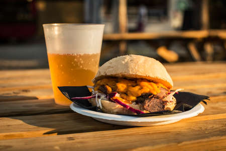 Delicious burger with roasted meal served on plate on wooden table with beer.の写真素材