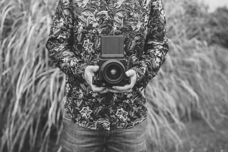 Crop unrecognizable man standing with film amera on background of grass.の写真素材