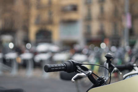 Black and chrome handlebars of modern bicycle parked on street in blur.の写真素材