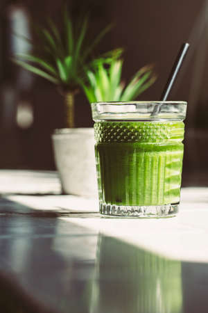 Green detox juice glass in a white tile tableの写真素材