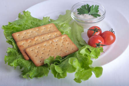 Crispy cracker with herbs and cherries. Still life of eating cookies with sauce and herbs and tomatoes.の写真素材