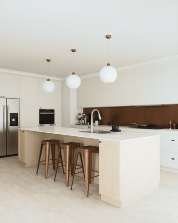 This kitchen features modern minimalism with stylish barstools and pendant lightingの写真素材