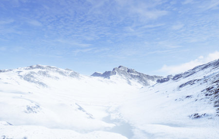 Behold the Majestic Aerial View of the SnowCapped Mountains Beneath a Clear Blue Skyの写真素材