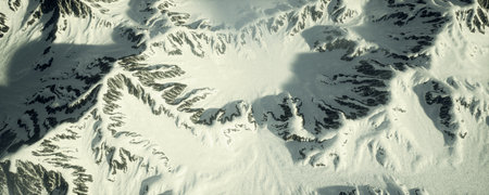 Behold the Majestic Aerial View of the SnowCapped Mountains Beneath a Clear Blue Skyの写真素材