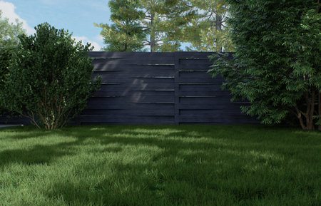 Green lawn against a background of a gray fence and trees.の写真素材