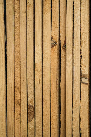 Close-up of neatly stacked, rough-cut wooden planks with visible grain and knots, forming a natural pattern.の写真素材